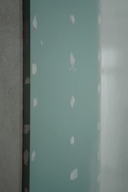 Freshly installed green drywall with white patches, ready for painting or finishing touches in home renovation.